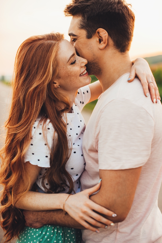 Beautiful,Young,Caucasian,Couple,Embracing,And,Smiling,While,Standing,Outdoors.