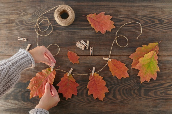 Homemade,Garland,Of,Colored,Autumn,Leaves.,Womans,Hands,Hanging,Leaves